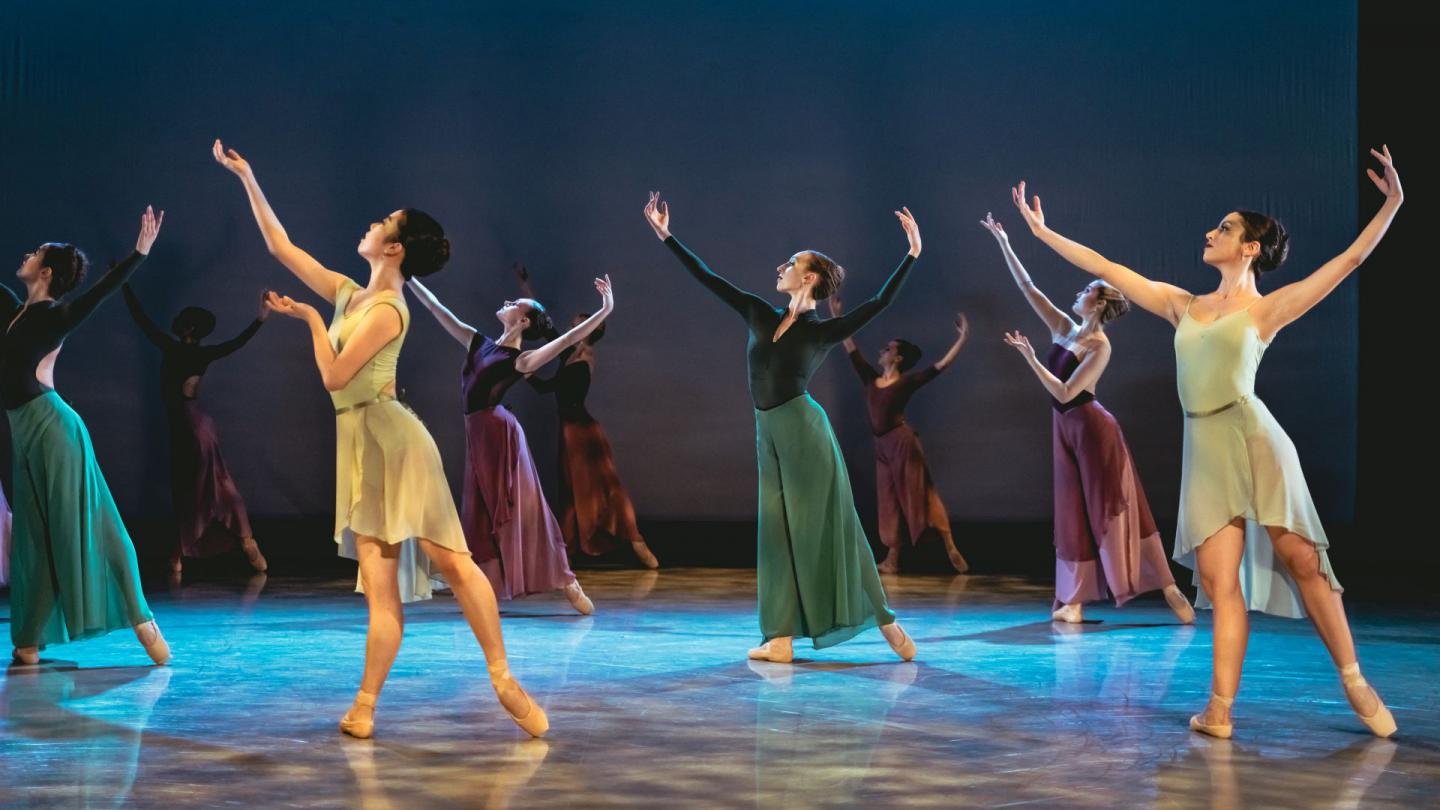 A group of dancers on stage in yellow, blue and green outfits