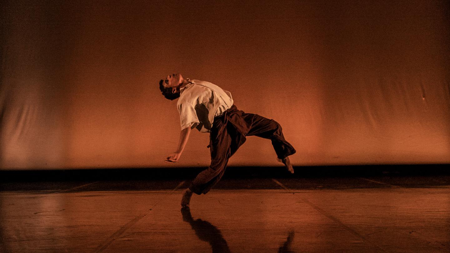 Dancer against a brown background, leaning and bending backwards