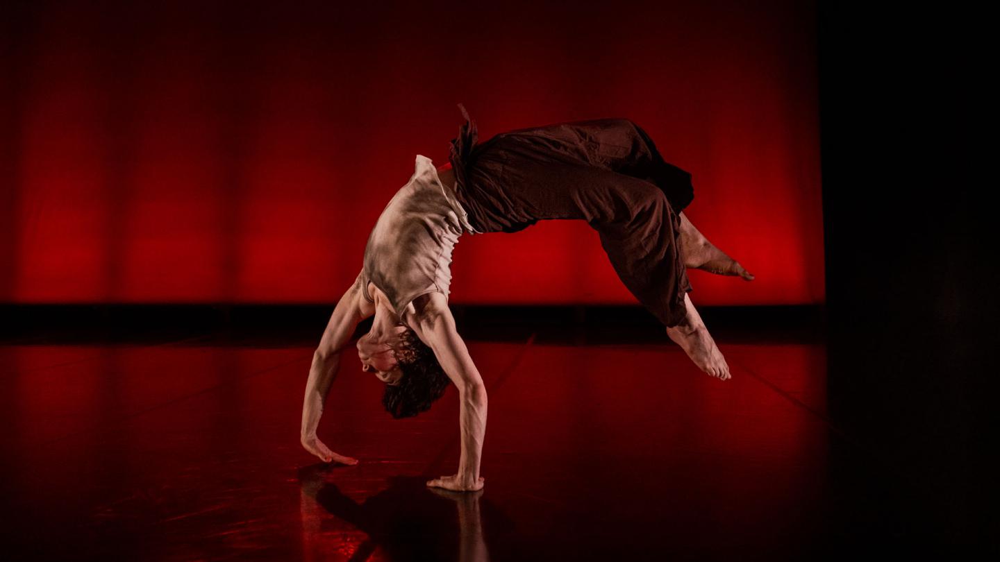 Dancer mid back-flip, hands against the floor, back arched, feet off the ground