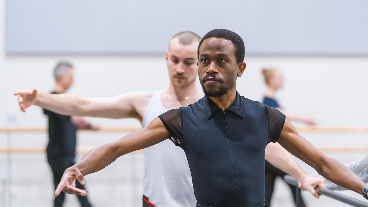 Male student dancer at the barre, holding a pose, his look intense