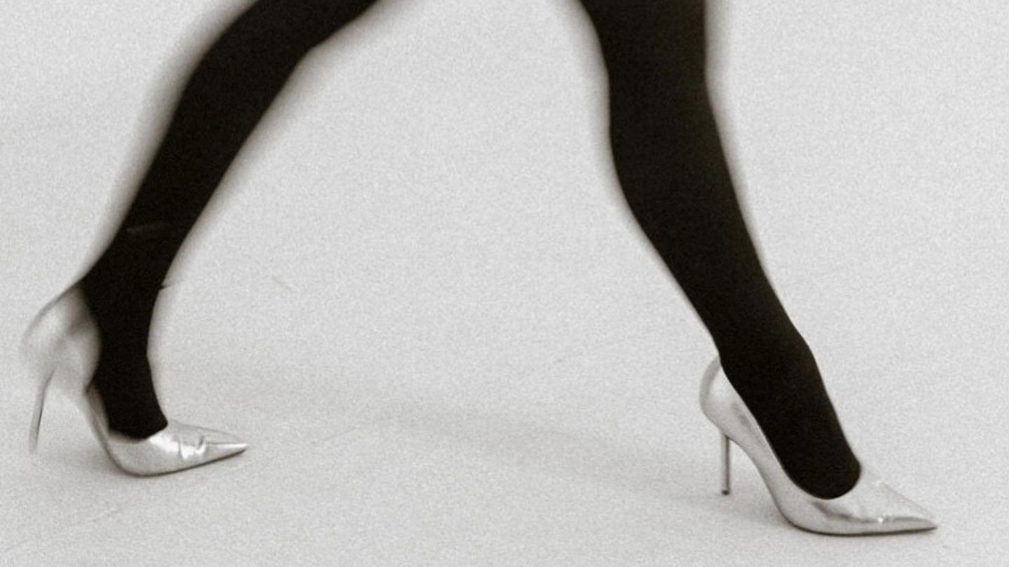 Legs wearing black tights and silver stilettos striding purposefully