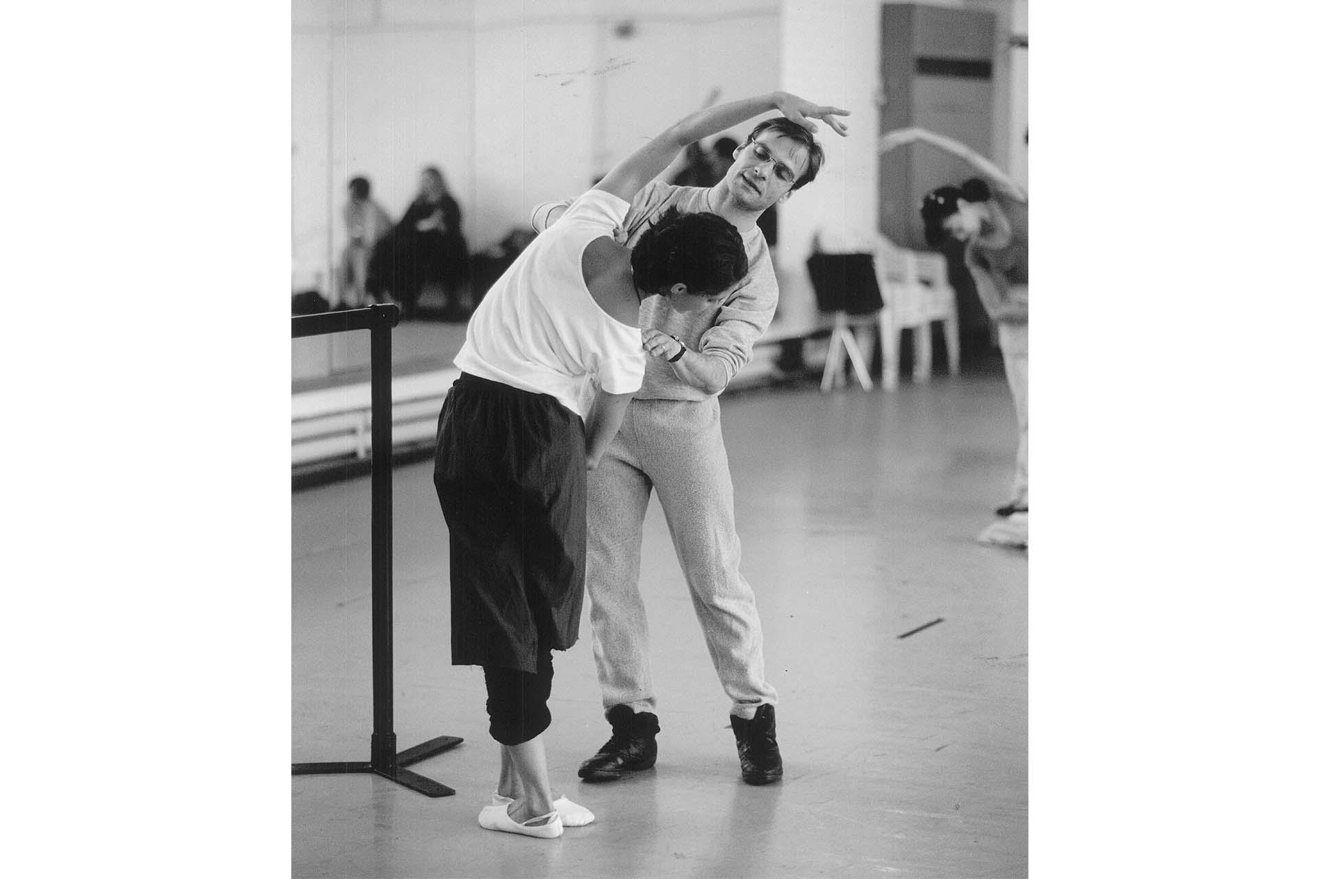 Stefano correcting the pose of a dancer in front of a barre