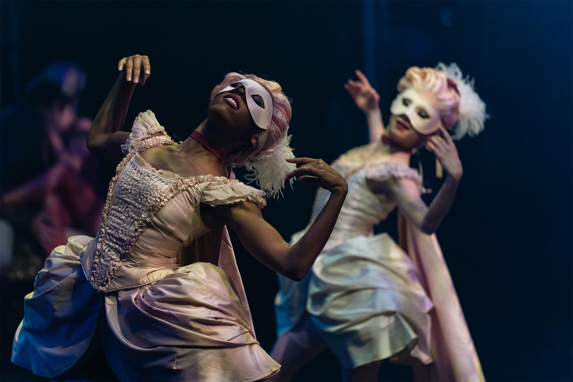 Female dancers wearing masks and 18th century costumes
