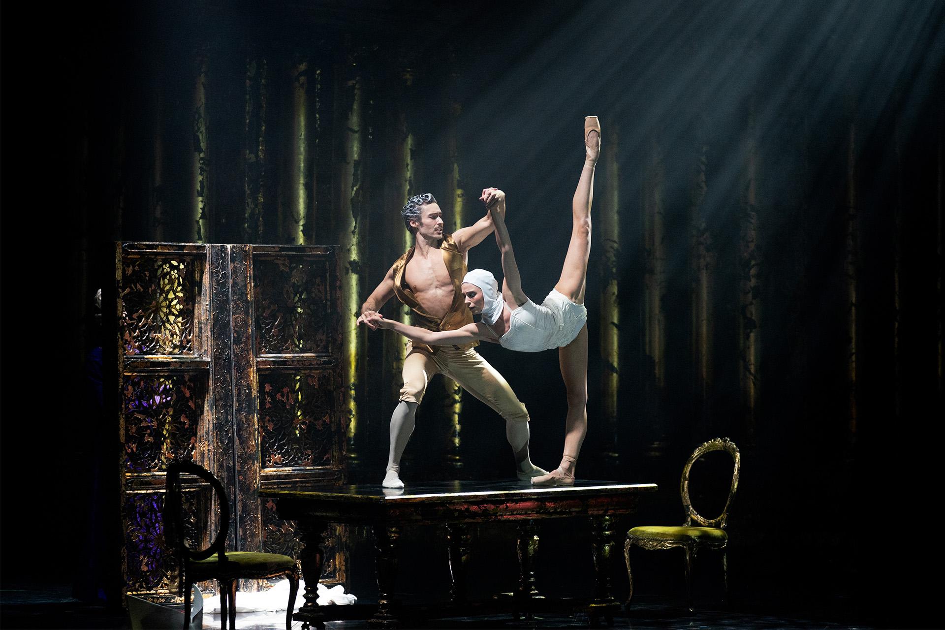 Casanova and M.M. on a table, M.M. leaning forward extending a leg vertically while Casanova supports her.