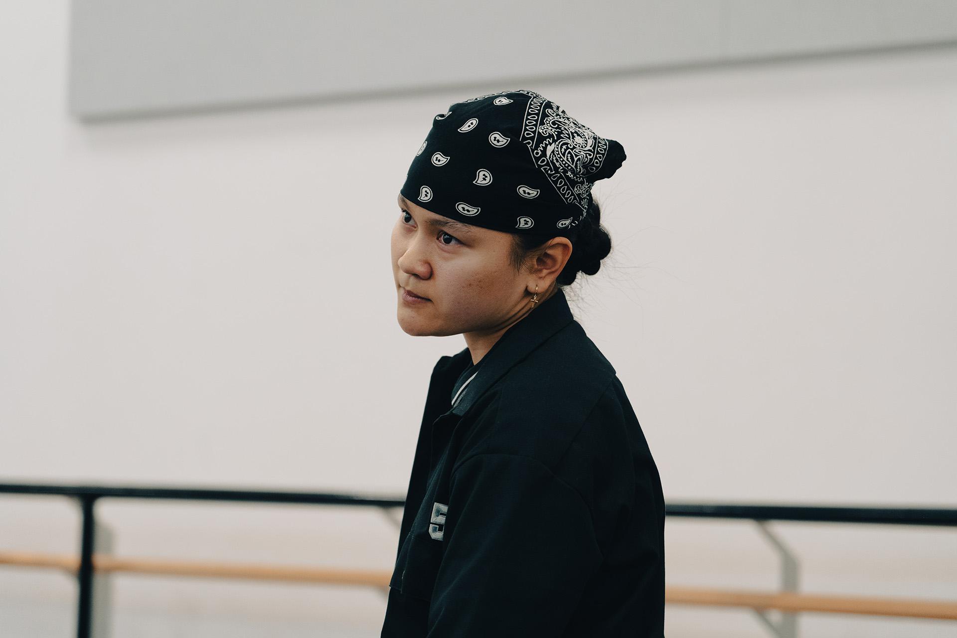 Dancer wearing a bandanna on their head looks intensely at something off camera