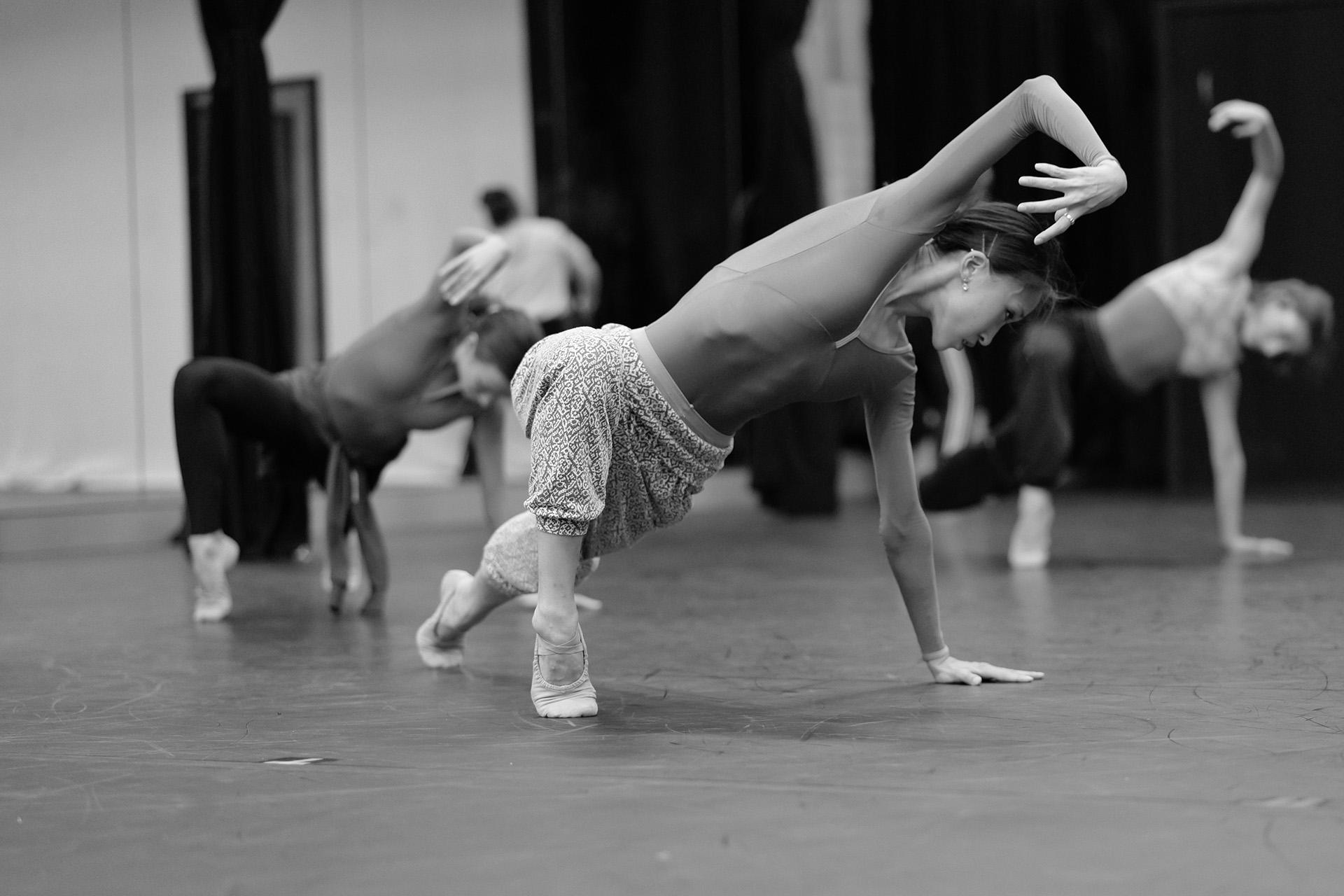 Dancer leaning on the ground holding one arm bent above her head