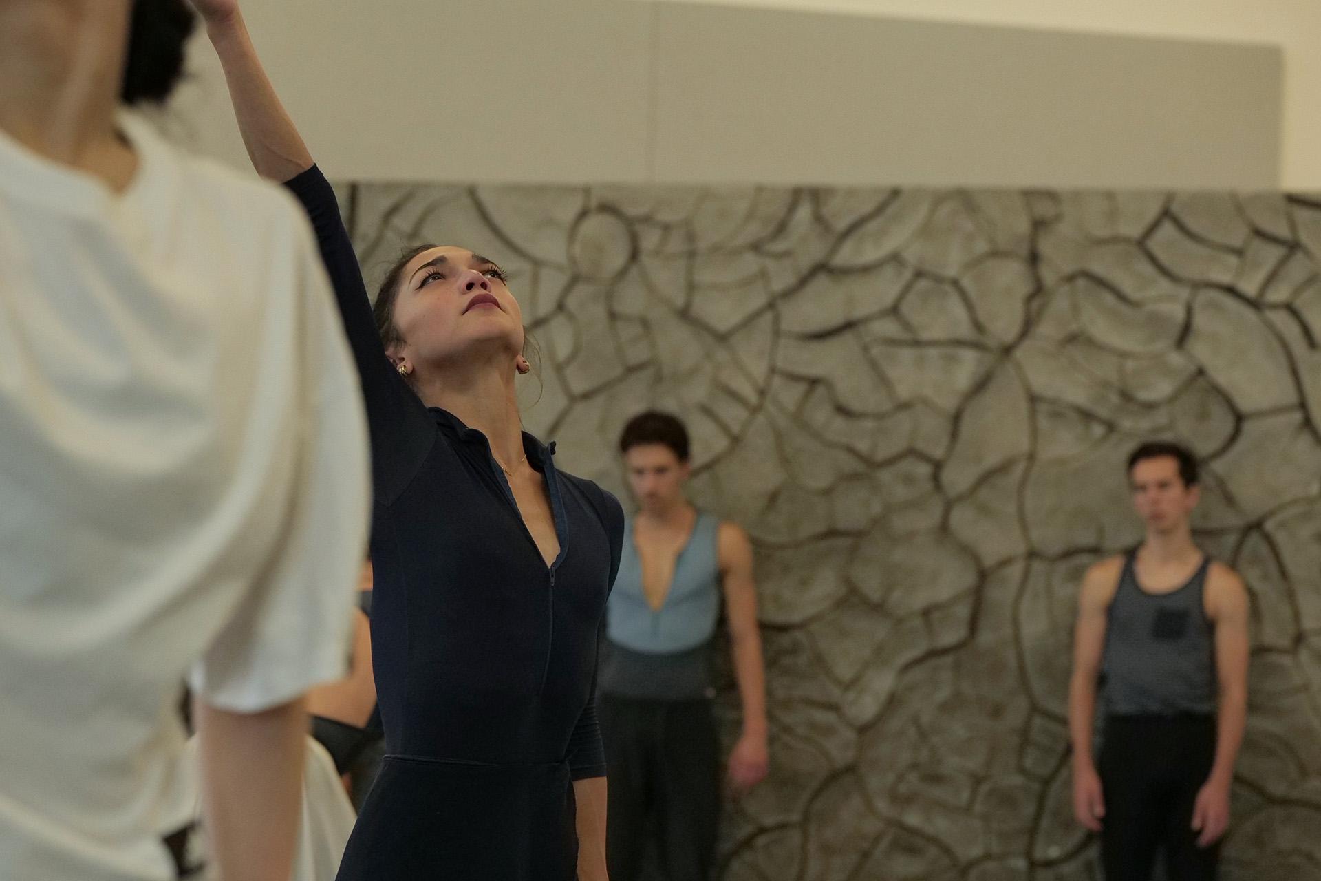 Dancer in dark vest reaches up and looks to the sky