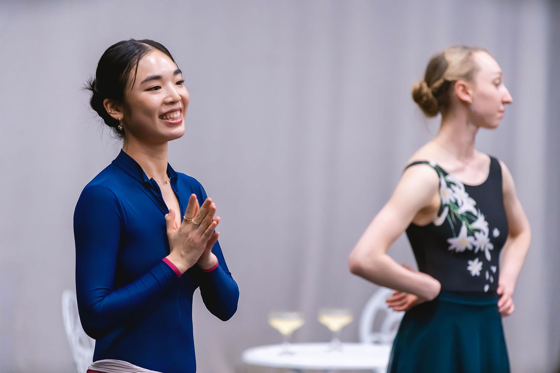 Woman dancer in a blue top smiling and holding her hands together