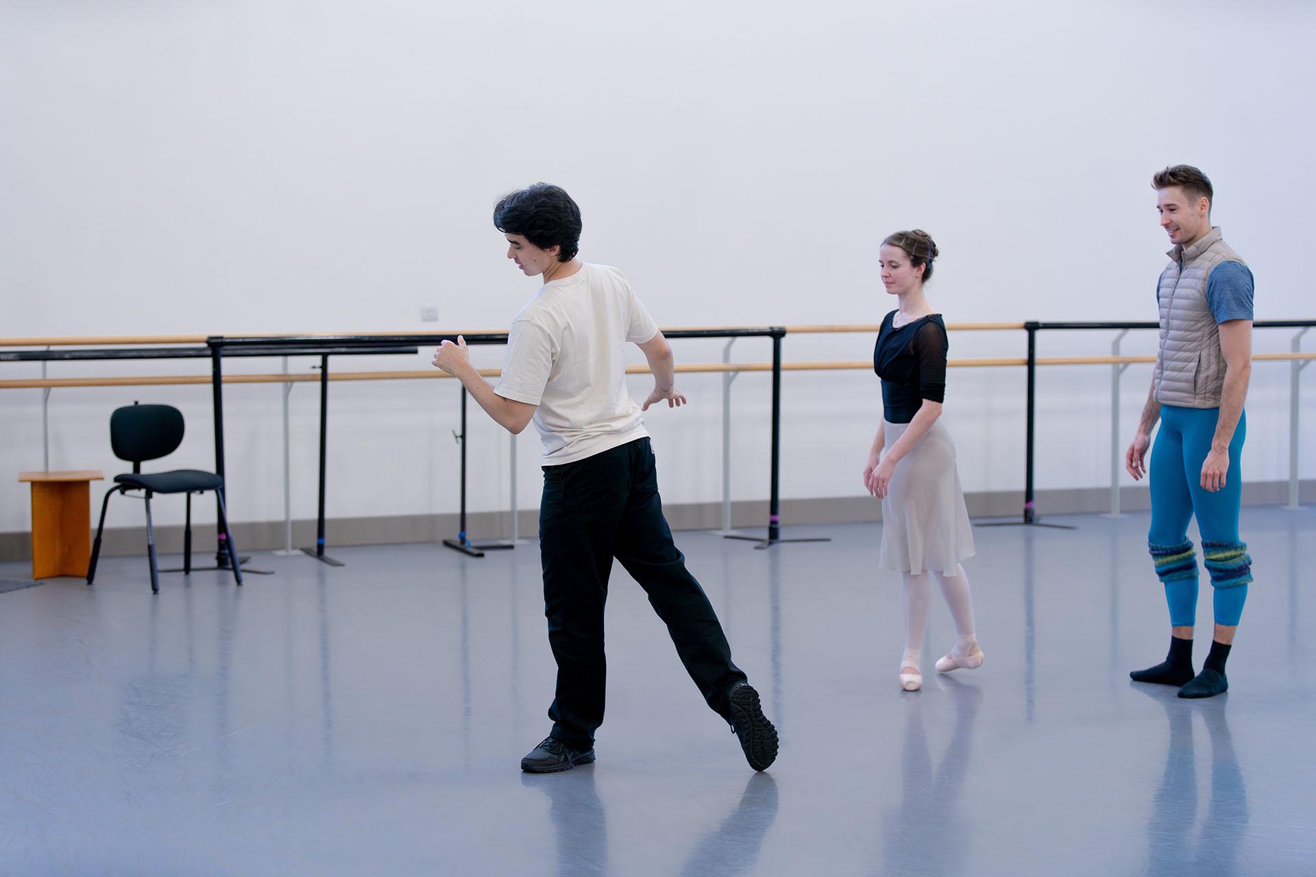 Choreographer marks out a position he want two onlooking dancers to perform.