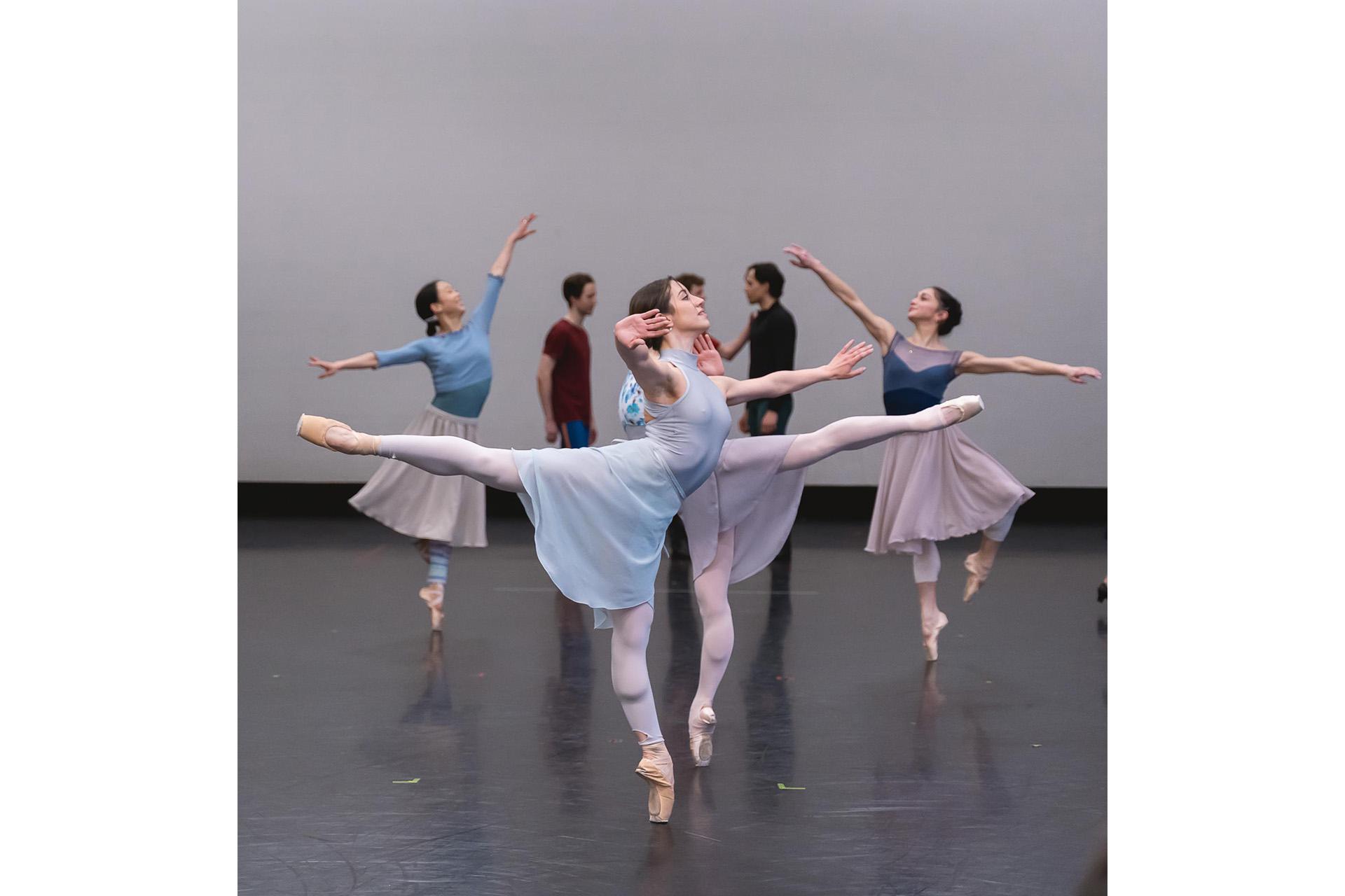 A group shot of two dancers in arabesque mirroring each other