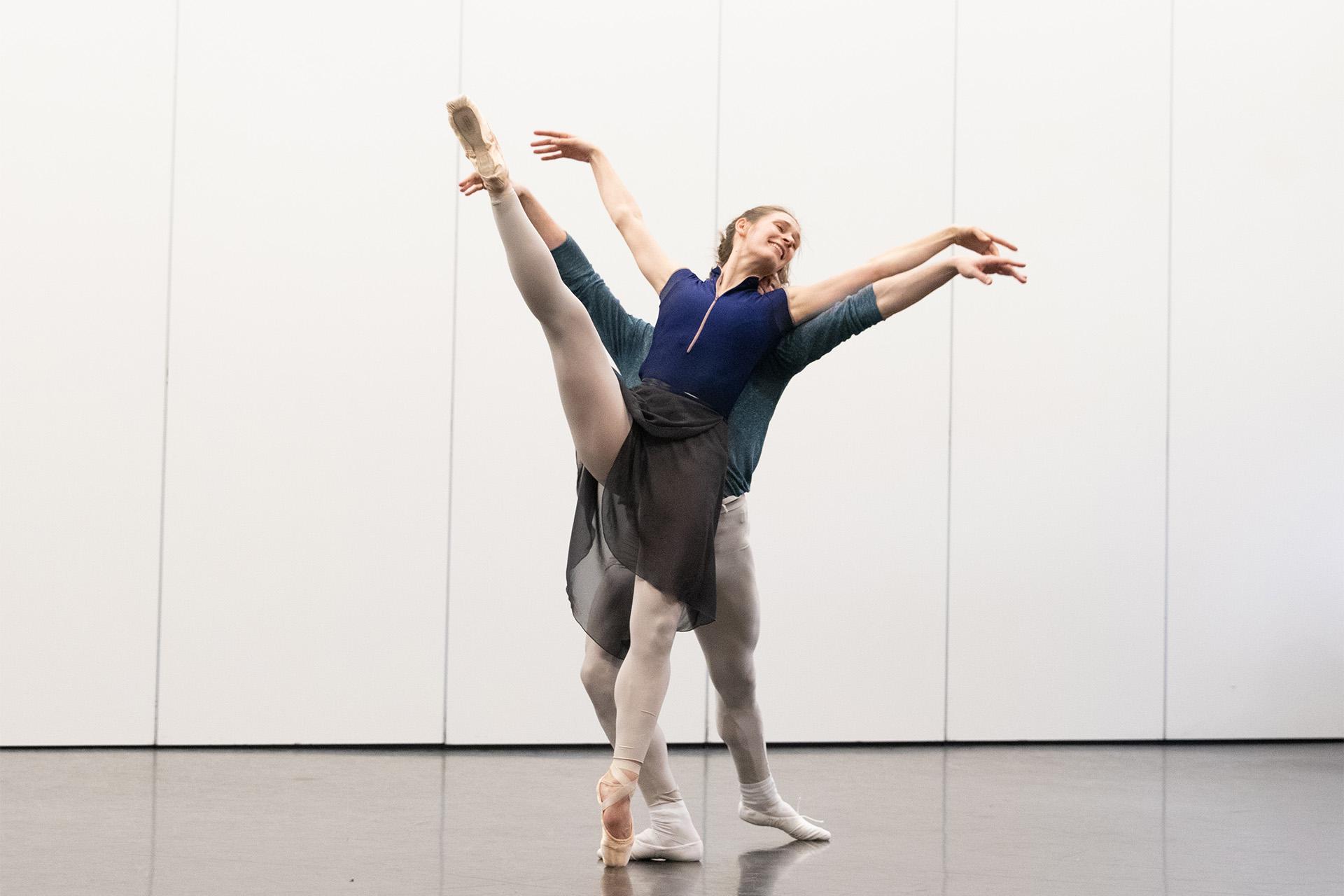 Two dancers stood with arms and one leg raised
