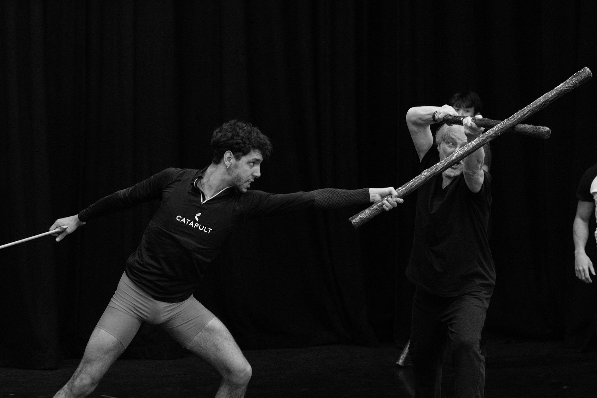 Black and white photo of man rehearsing fighting with a staff on place of a sword
