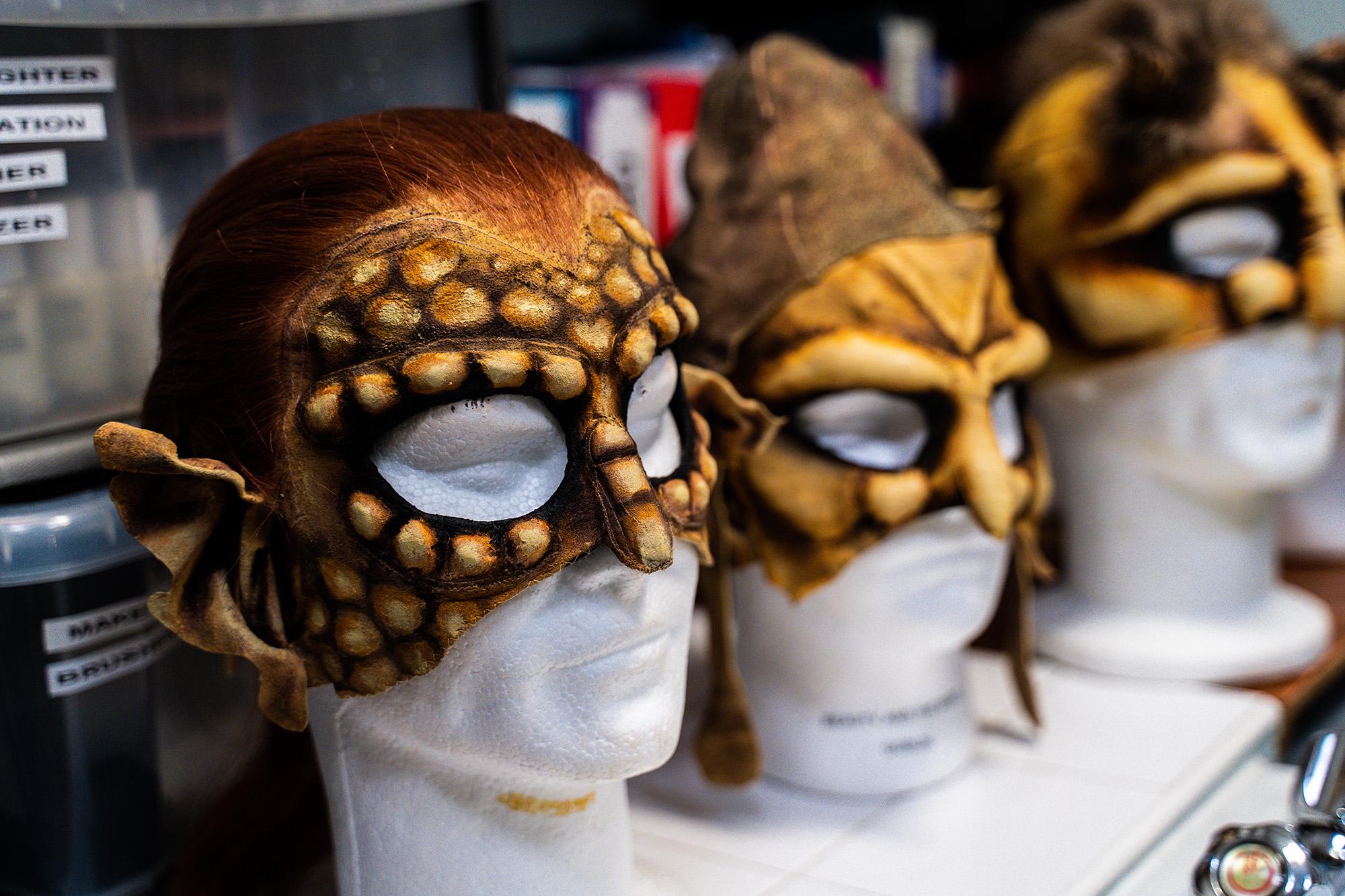 Three gold masks on mannequins with scales and goblin features
