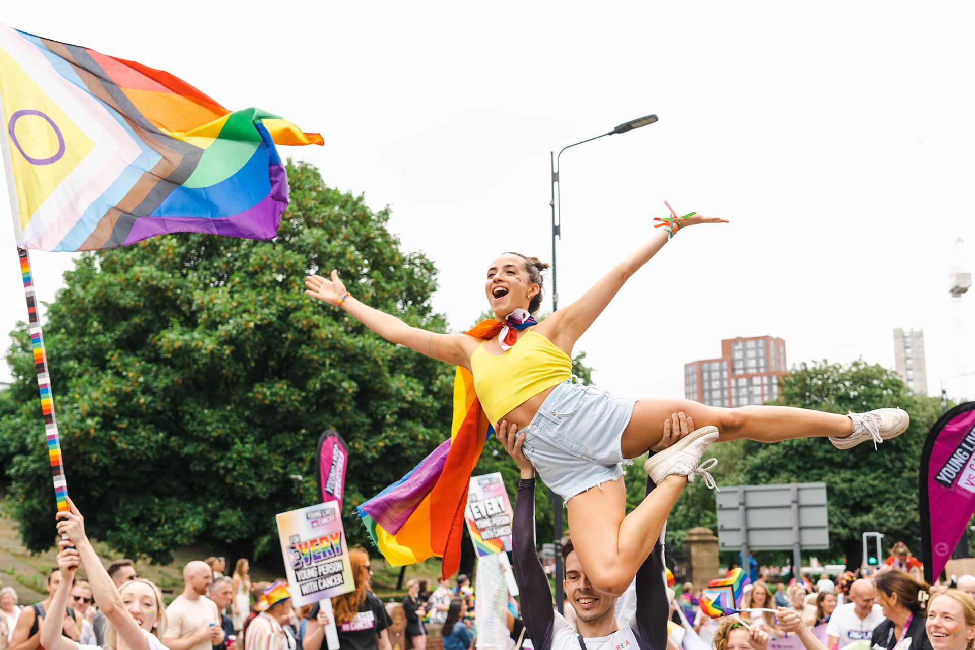 Northern Ballet dancers at Leeds Pride 2024, on lifted ballet style, arms wide and smiling happily