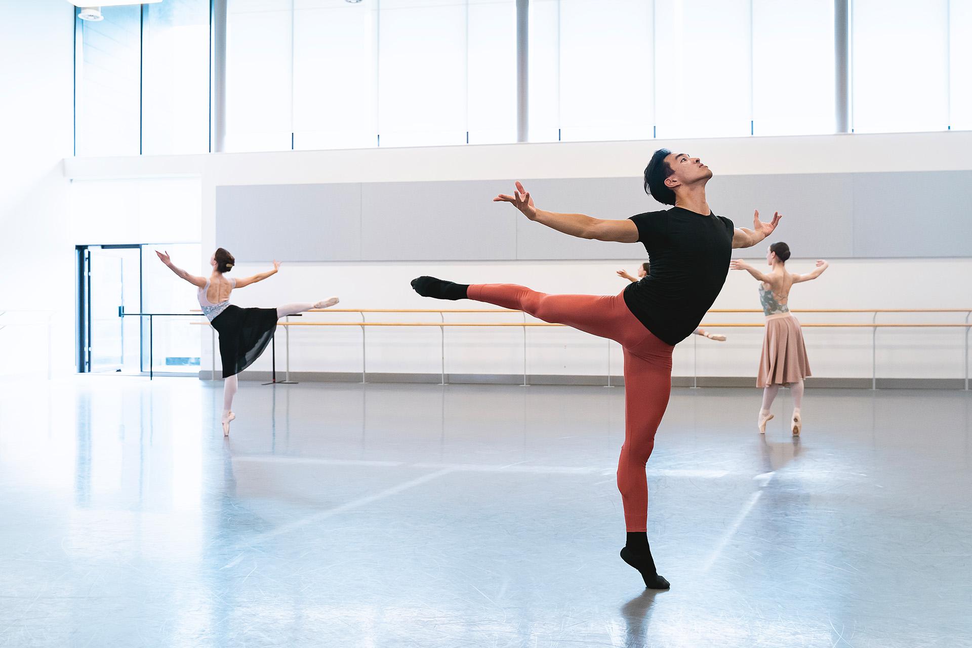 Dancer in rehearsal in red leggings and black T-Shirt standing proudly arabesque