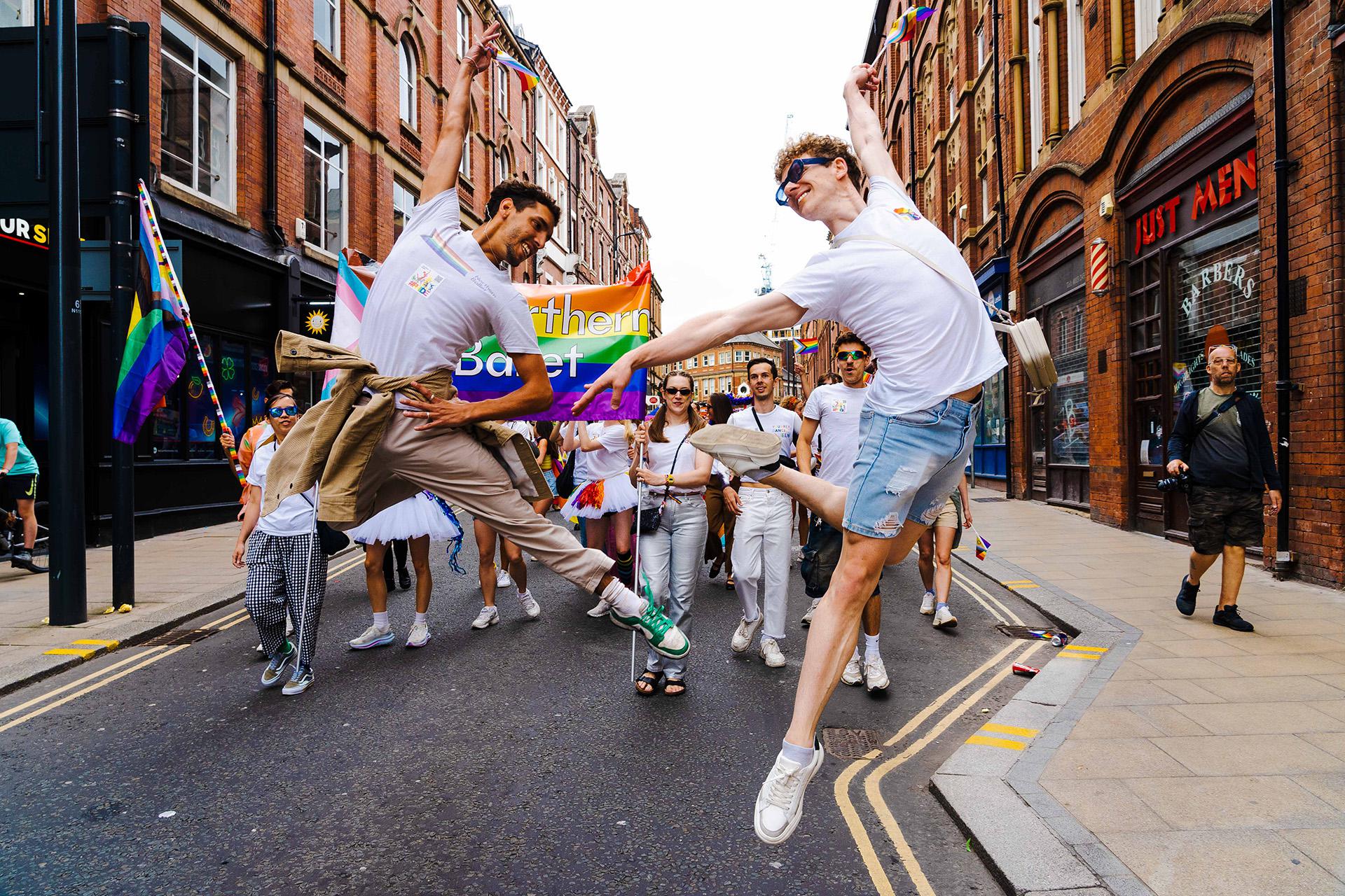 Dancers of York Street in Leeds each leaping and striking a pose while smiling broadly during the Leeds Pride parade