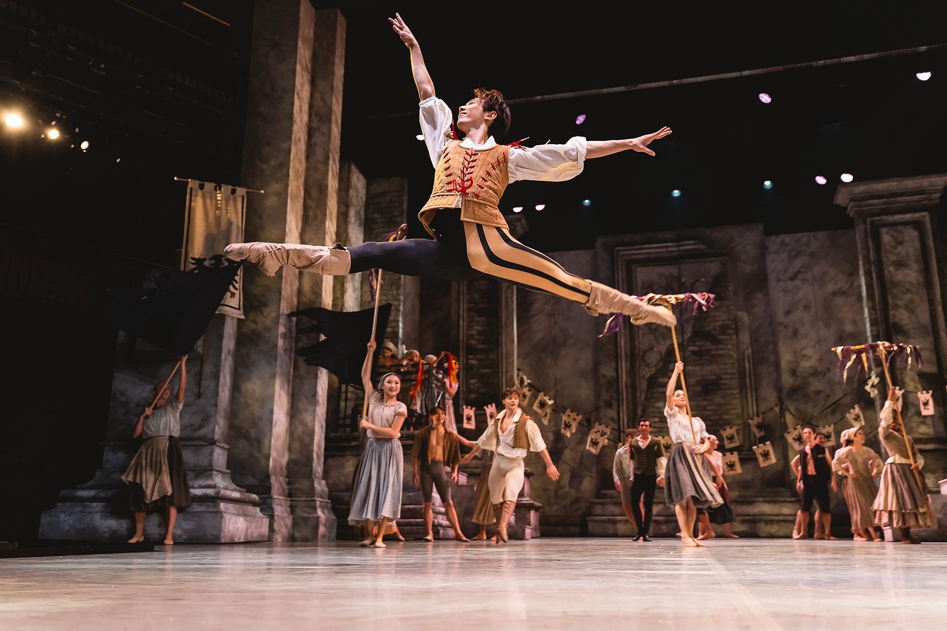 Leaping his above the stage while other cast members look on.