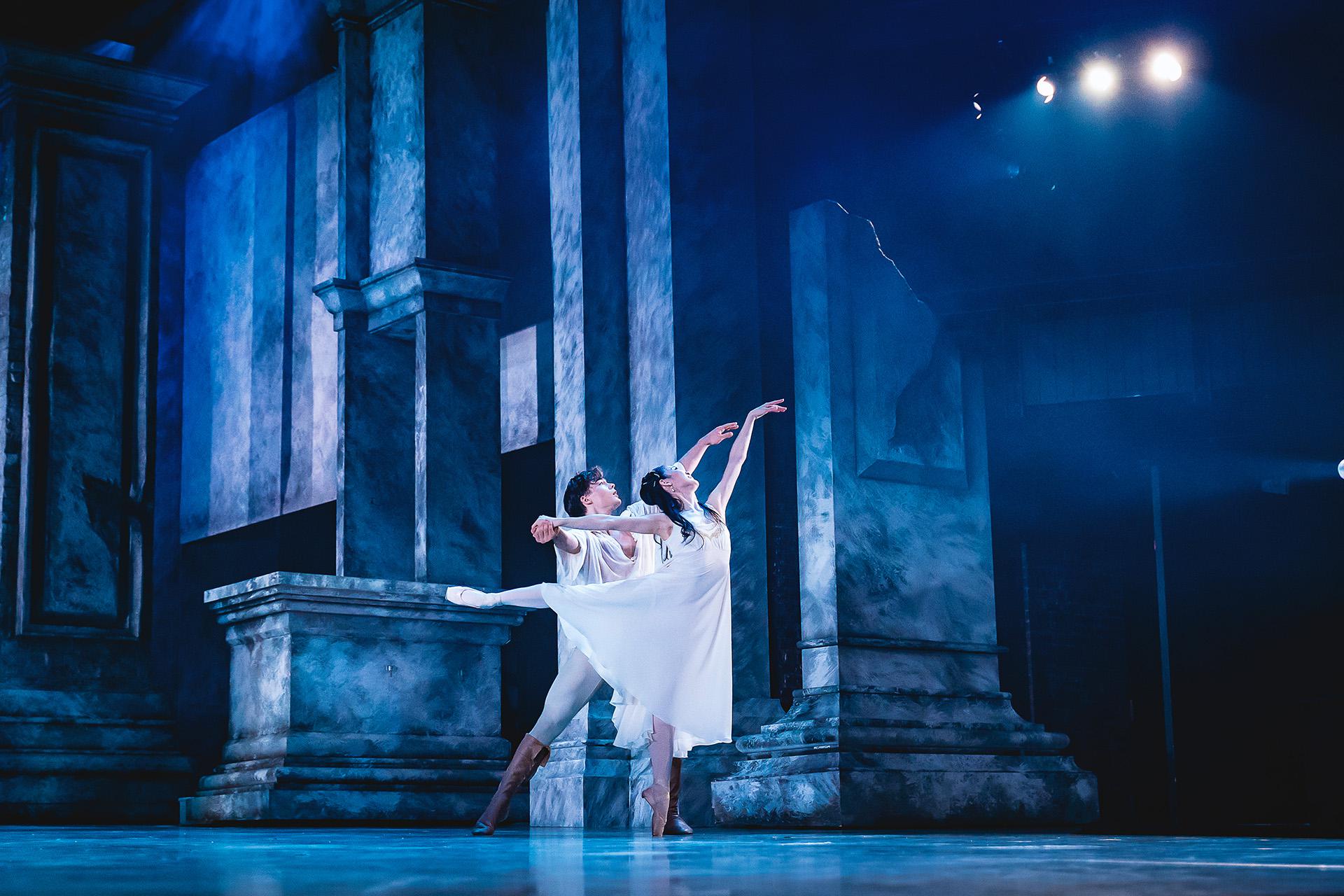 In cool blue light, Romeo and Juliet dance lovingly and closely across the stage