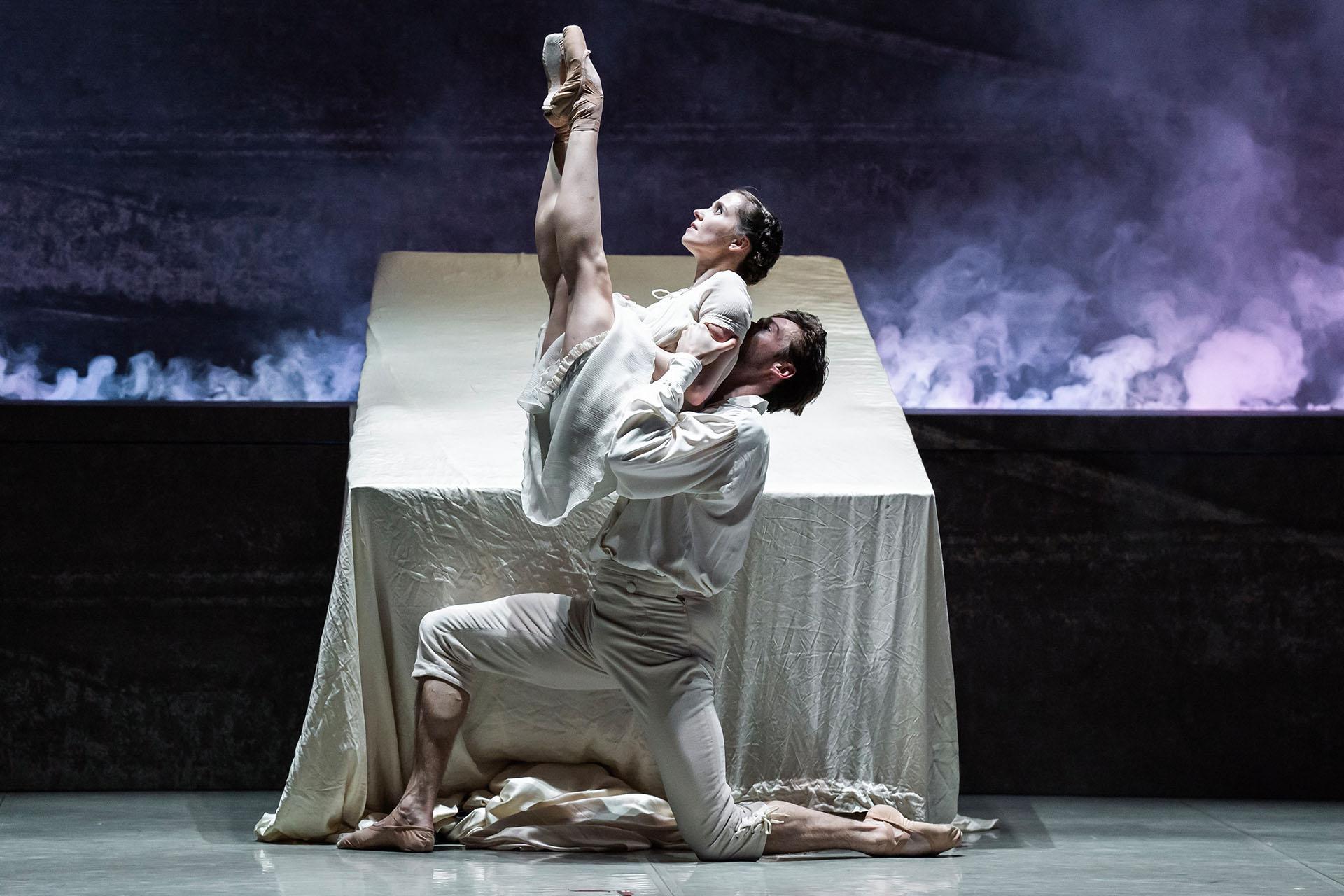 Dressed in their white night clothes and in front of their bad, Mr Rochester lifts Jane, her legs together and pointed at the sky