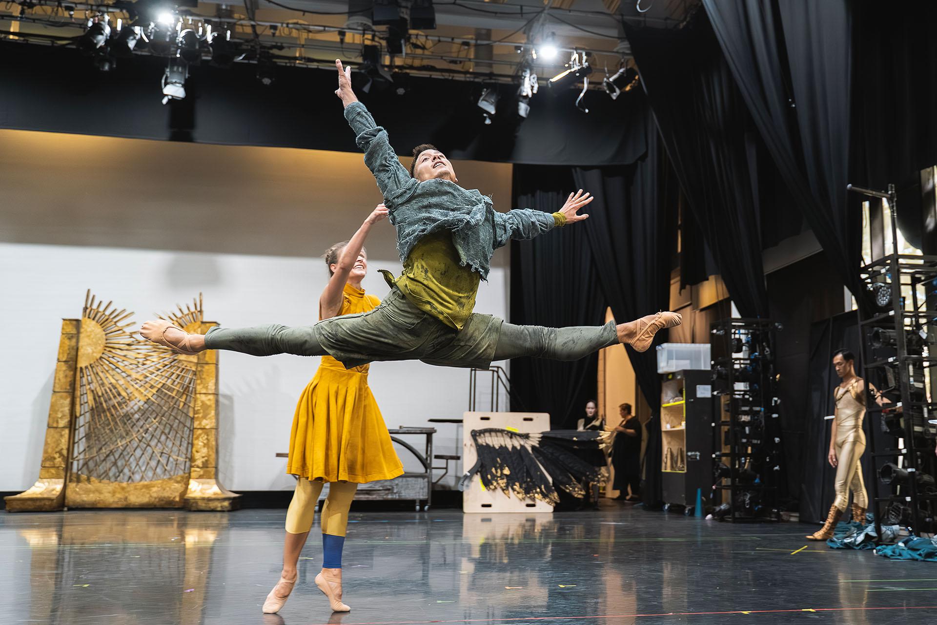 Man leaps (grand jete) across the stage dressed in green