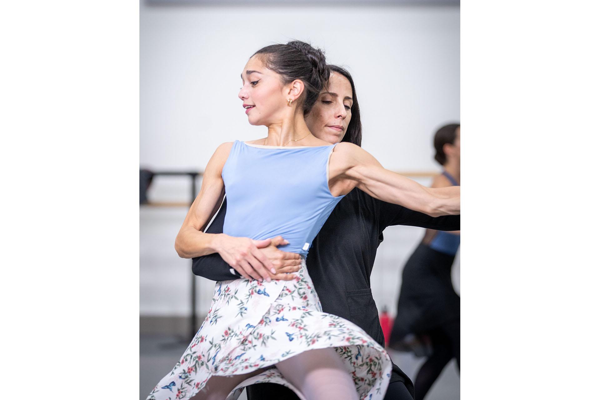 Dancer in pale blue top and flowery dress being lifted from behind by the choreographer