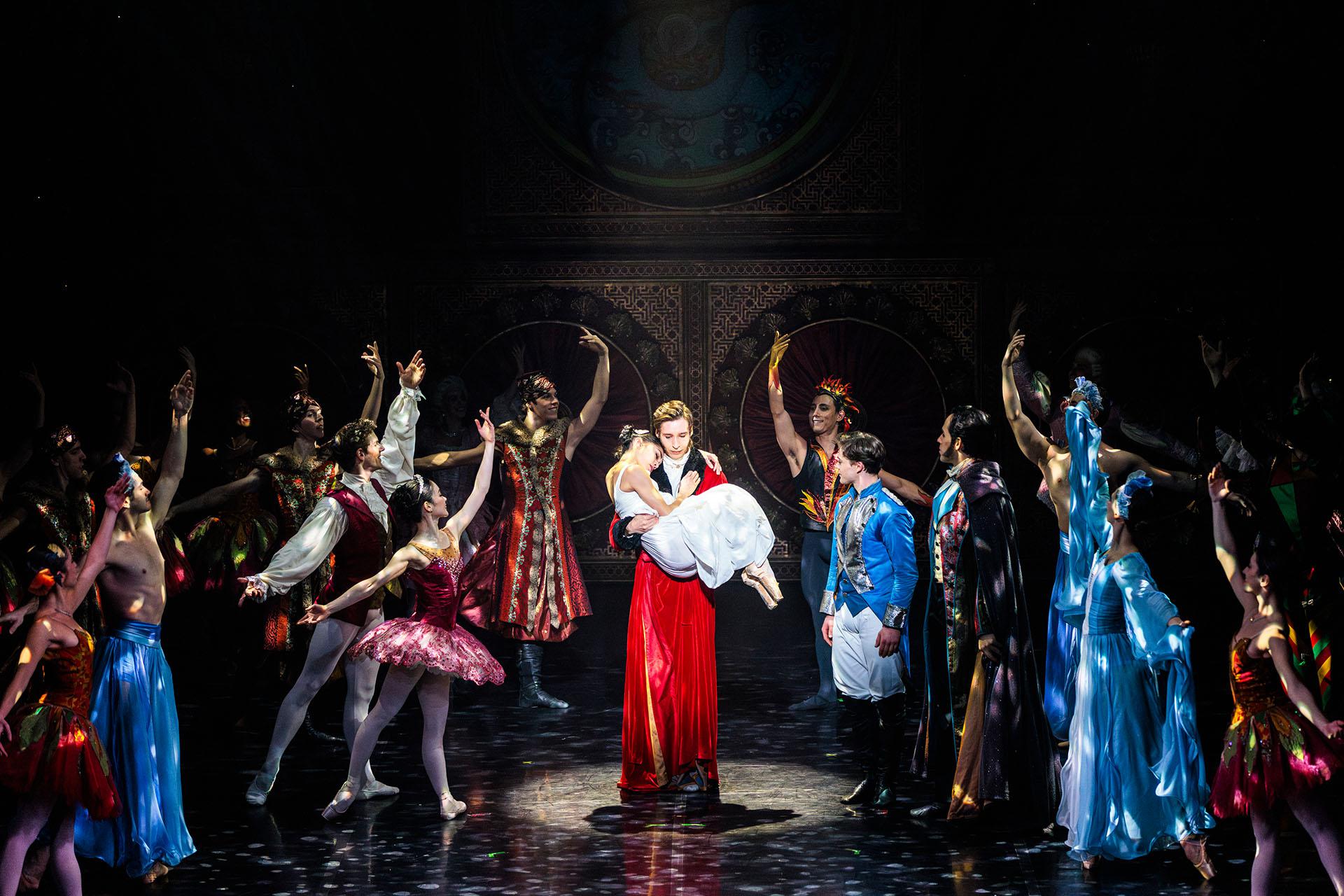 Clara's father carries her while she sleeps, the magical characters from her dreams look on