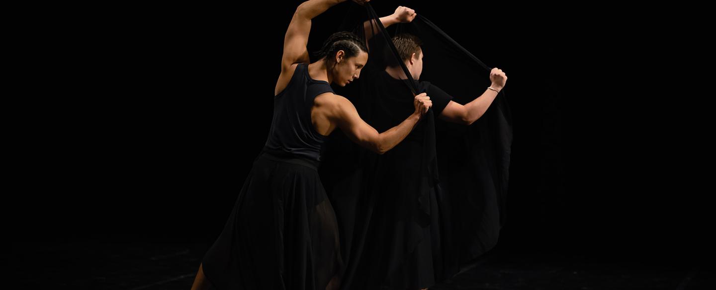Two dancers reflect each other, showing the strength of their arms