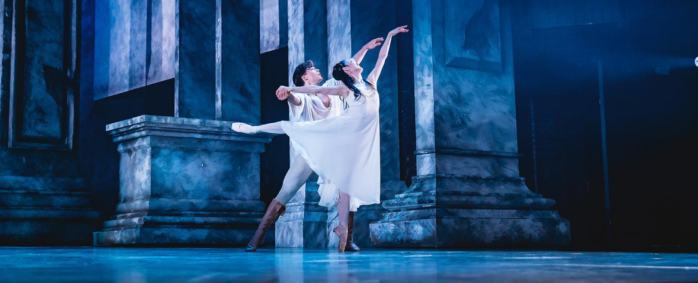 In cool blue light, Romeo and Juliet dance lovingly and closely across the stage