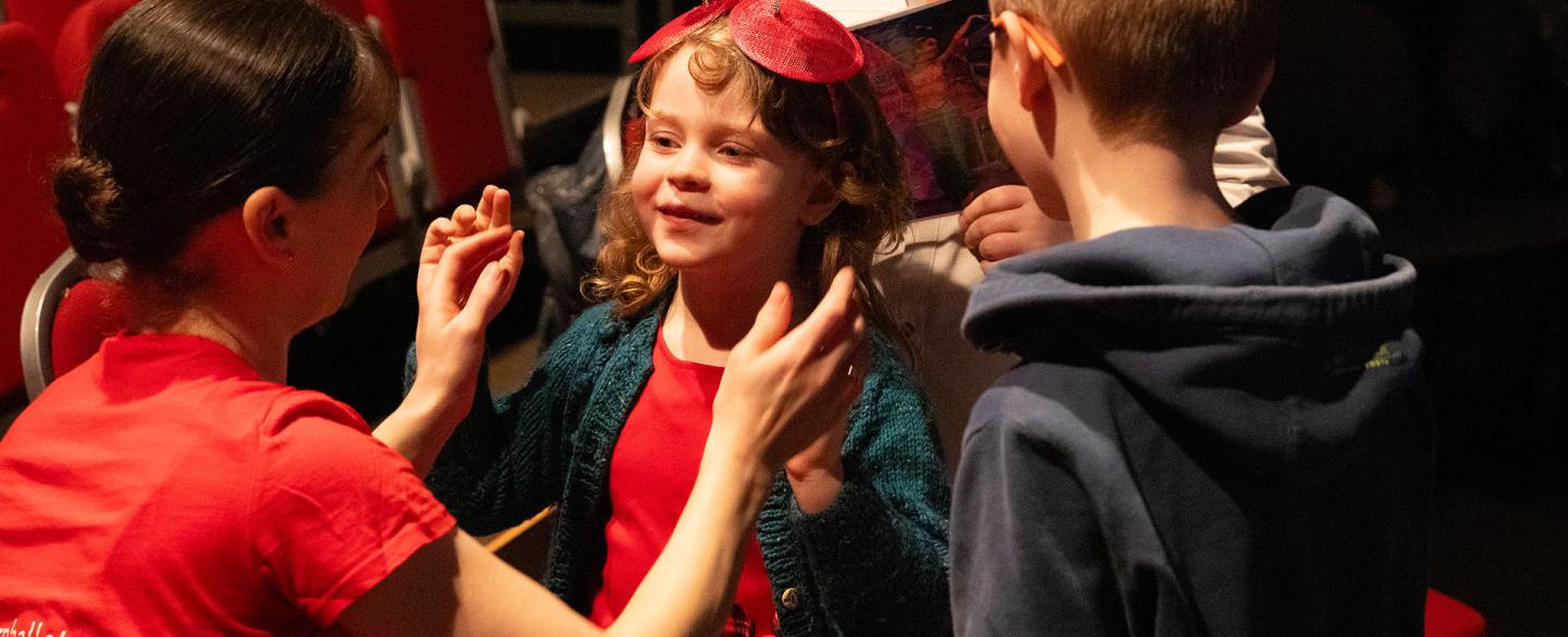 A child is wearing part of the costume for a Children's Ballet to feel closer to the action