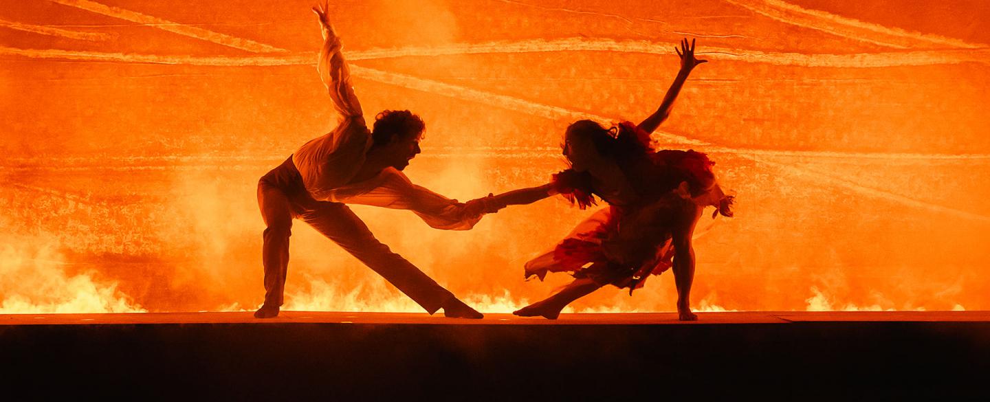 Silhouetted by bright, blazing orange, Rochester and Bertha at the same time pull away and hold on to each other