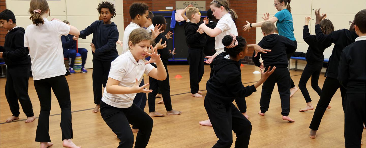 School children in a PE hall practice moves and dancing in a safe place