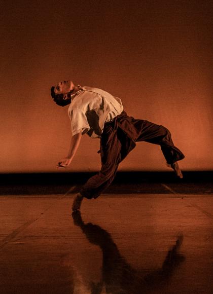 Dancer against a brown background, leaning and bending backwards