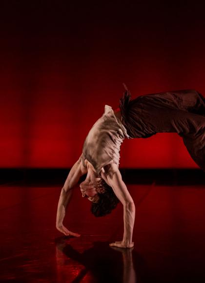 Dancer mid back-flip, hands against the floor, back arched, feet off the ground