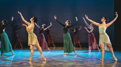 A group of dancers on stage in yellow, blue and green outfits