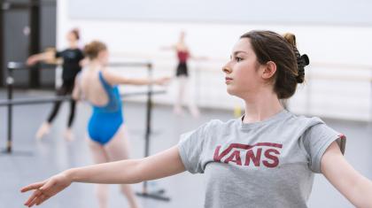 A young woman leaning backwards on a ballet barre