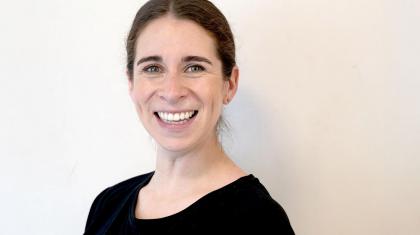 Woman with dark hair and wearing a black top smiles broadly at the camera