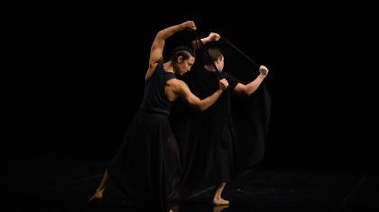 Two dancers reflect each other, showing the strength of their arms