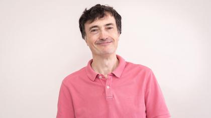 Man in pink polo-neck shirt, short dark hair greying at the temples, smiling