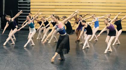 Students copying the ballet pose performed by a dancer in front of them