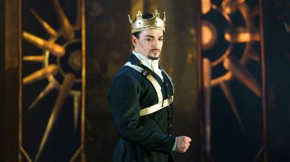 Dressed in black and wearing a crown, Vortigern looks firm yet pensive