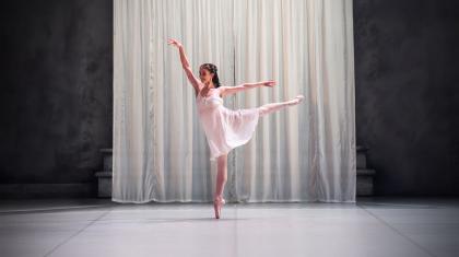 Dancer in white shift standing arabesque en pointe